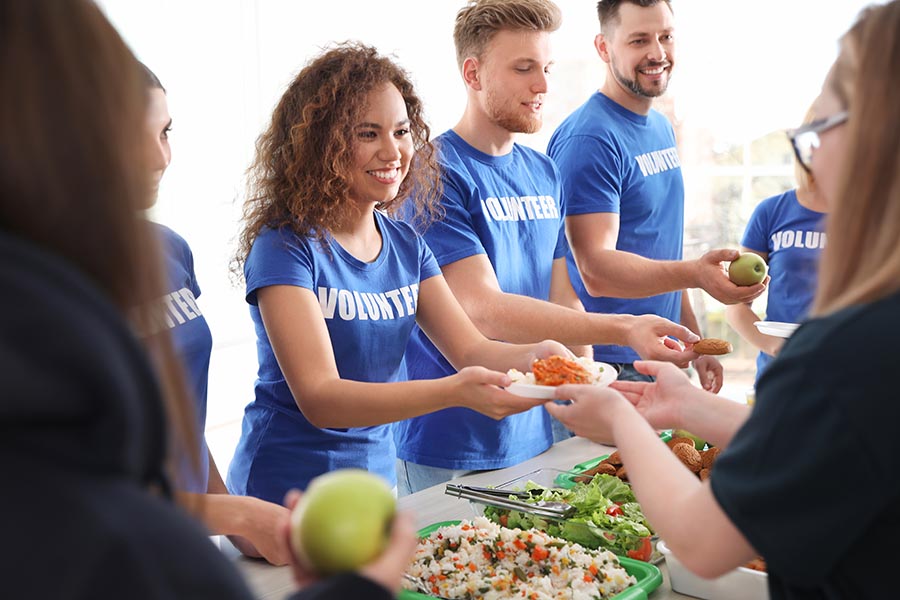 Specialized Business Insurance - Volunteers in Matching Blue Shirts Hand Out Meals During a Community Event